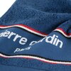 Przedstawiony jest granatowy ręcznik z widocznym napisem "pierre cardin paris" oraz ozdobnym paskiem w kolorach czerwonym, białym i czarnym. Materiał ręcznika ma teksturę frotte.