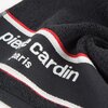Czarny ręcznik z widocznym napisem "pierre cardin paris" oraz ozdobnymi paskami w kolorach białym i czerwonym. Materiał ręcznika jest puszysty i miękki.