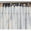 Zasłona w kolorze grafitowo-beżowym zawieszona na metalowym karniszu, z widocznymi marszczeniami i białymi haczykami. Materiał ma delikatny wzór i jest lekko prześwitujący.