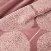 Różowy koc z widocznym wzorem w postaci dużych, okrągłych kształtów o teksturze przypominającej splot nici. Materiał wygląda na miękki i puszysty, z delikatnym połyskiem na wzorze.