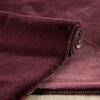 Zdjęcie przedstawia bordowy dywanik łazienkowy o prostokątnym kształcie, częściowo zwinięty na jasnym tle. Materiał dywanika ma miękką, puszystą fakturę z widocznymi szwami na krawędzi.