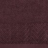 Bordowy ręcznik o wymiarach 30 x 50 cm z widocznym wzorem w jodełkę na dolnym pasku. Materiał ma teksturę frotte, a wzór dodaje elegancji.