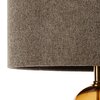Beżowo-złota lampa podłogowa z teksturowanym abażurem i błyszczącą, złotą podstawą. Abażur ma wyraźną, plecioną strukturę materiału.