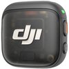 Czarny, kwadratowy nadajnik z zaokrąglonymi krawędziami, na którym widoczne jest logo "DJI". Na boku znajdują się dwa przyciski, jeden z pomarańczowym akcentem, oraz zielona dioda.