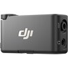 Czarny odbiornik z logo "DJI" na obudowie, z widocznymi portami oznaczonymi jako "OUT" oraz symbolem słuchawek. Na górze znajduje się pokrętło.
