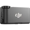 Czarny odbiornik z widocznym logo "DJI" na obudowie, z boku znajdują się przyciski i pokrętło. Produkt ma gładką powierzchnię i kompaktowy kształt.