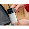 Na zdjęciu widoczny jest szary powerbank z wyświetlaczem pokazującym 62% naładowania oraz logo "tracer" poniżej ekranu. Urządzenie trzymane jest w dłoniach, a w tle znajduje się fragment torby.