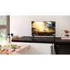Na zdjęciu znajduje się telewizor SHARP 24HF2765E 24" LED Google TV ustawiony na blacie kuchennym, wyświetlający obraz gotującego się dania w patelni. Obok telewizora widoczne są książki kucharskie, a na blacie kuchennym leżą różne składniki i przybory ku
