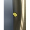 Na zdjęciu widoczna jest metaliczna powierzchnia w złotym kolorze z przyklejoną żółtą strzałką skierowaną w bok. Tło jest jednolite i ma szary odcień.