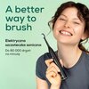 Na zdjęciu widoczna jest osoba trzymająca czarną szczoteczkę soniczną z napisem "beurer" na uchwycie. Obok znajduje się tekst: "A better way to brush. Elektryczna szczoteczka soniczna. Do 80 000 drgań na minutę".