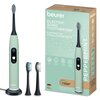 Soniczna szczoteczka do zębów w miętowym kolorze stoi na podstawce obok dwóch wymiennych końcówek, a obok znajduje się pudełko z napisem "beurer ELECTRIC SONIC TOOTHBRUSH ELEKTRISCHE SCHALLZAHNBÜRSTE" oraz "PEPPERMINT". Na pudełku widoczne są ikony przeds