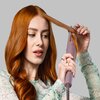 Osoba używa lokówki do stylizacji włosów, trzymając pasmo włosów w urządzeniu. Lokówka to model REMINGTON Airwave CI8930 43-30 mm.