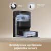 Czarny robot sprzątający znajduje się na granicy podłogi drewnianej i dywanu, z widocznymi śladami kurzu i brudu. Na obrazie widnieje tekst: "100% skuteczność zbierania dużych cząstek", "13 000 Pa" oraz "Układ ssania Vormax™ o mocy 13 000 Pa".