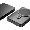 Na zdjęciu widoczny jest szary powerbank z okrągłym wzorem na powierzchni, obok którego znajduje się drugi, podobny obiekt. Powerbank posiada port USB-C, przycisk oraz cztery diody LED wskazujące poziom naładowania.