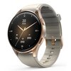 Złoto-beżowy smartwatch z okrągłą tarczą, na której wyświetlane są godzina, data oraz ikony dotyczące zdrowia i aktywności fizycznej. Pasek zegarka jest w jasnym odcieniu, a koperta ma metaliczne wykończenie.
