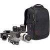 Czarny plecak fotograficzny z widocznym logo "MANFROTTO" stoi obok zestawu sprzętu fotograficznego, w tym aparatów, obiektywów i drona. Plecak ma kilka zamków błyskawicznych i czerwone akcenty na dolnej części.