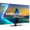 Telewizor marki PHILIPS z widocznym napisem "AMBILIGHT tv OLED" na ekranie, przedstawiającym postać w skafandrze kosmicznym stojącą w wodzie na tle zachodzącego słońca. Logo PHILIPS znajduje się w lewym górnym rogu ekranu.