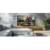 W nowoczesnym salonie znajduje się telewizor z wyświetlonym interfejsem, na którym widoczne są aplikacje takie jak Netflix, Prime Video i YouTube oraz grafika z napisem "Fallout". Na ścianie obok telewizora widnieją napisy "Panasonic TV PREMIUM", "fire tv