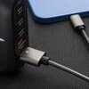 Srebrny kabel USB-Lightning o metalicznym wykończeniu jest podłączony do urządzenia z widocznym logo "FORCELL" na wtyczce. Kabel leży na ciemnej, teksturowanej powierzchni, tworząc delikatną pętlę.
