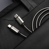 Na zdjęciu widać srebrny kabel USB-C - USB-C podłączony do czarnego urządzenia z kilkoma portami, w tym oznaczonymi jako "PD 3.1", "USB-C1", "USB-C2" oraz "USB-C3". Obok kabla znajduje się niebieskie urządzenie, do którego drugi koniec kabla jest również 