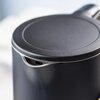 Zdjęcie przedstawia czajnik elektryczny w kolorze czarnym, z widocznym górnym wiekiem i wylewką. Powierzchnia czajnika jest matowa, a jego kształt jest zaokrąglony.