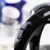 Zdjęcie przedstawia czajnik elektryczny z przezroczystym korpusem, w którym widać gotującą się wodę z bąbelkami. Uchwyt czajnika jest czarny, z widocznym przyciskiem oznaczonym napisem "PUSH".