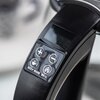 Zbliżenie na górną część czajnika elektrycznego z metalową pokrywą i czarnym uchwytem. Na uchwycie znajduje się wyświetlacz z niebieskim podświetleniem pokazujący "99" oraz przyciski z symbolami: plus, minus, filiżanka, "KEEP WARM" i "BOIL".