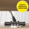 Odkurzacz z uniwersalną szczotką z oświetleniem, widoczny podczas sprzątania pod meblem, z rozsypanymi drobinami na podłodze. W prawym górnym rogu znajduje się żółte koło z napisem: "SZCZOTKA UNIWERSALNA Z OŚWIETLENIEM".