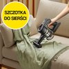 Na zdjęciu widoczny jest odkurzacz ręczny używany do czyszczenia zielonego koca na beżowej kanapie, z widocznymi kłębami sierści. W lewym górnym rogu znajduje się żółte koło z napisem "SZCZOTKA DO SIERŚCI".