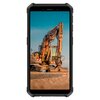 Smartfon wyświetla zdjęcie koparki na tle nieba, z widocznym napisem "LIEBHERR" na ramieniu maszyny. Koparka stoi na żwirowym podłożu, a w tle widać jasne niebo.