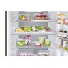 Wnętrze lodówki wypełnione różnorodnymi produktami spożywczymi, w tym owocami, warzywami, ciastem oraz napojami w puszkach. Na drzwiach lodówki widoczne są opakowania z masłem oraz słoiki z przetworami.