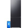 Na zdjęciu widoczna jest lodówka w kolorze grafitowej stali z logo "SAMSUNG" na górnych drzwiach oraz smartfon z wyświetlonym logo "SmartThings". Produkt ma nowoczesny design i gładką powierzchnię.