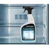 Butelka z rozpylaczem o pojemności 1 litra, oznaczona jako "FRISCHER Professional Kühlschrankreiniger Refrigerator Cleaner", stoi na szklanej półce wewnątrz lodówki. Etykieta zawiera grafikę lodówki oraz napisy "FOR KÜHLSCHRÄNKE | FOR REFRIGERATORS".