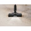Odkurzacz z widocznym logo "Hoover" i napisem "anti-twist" na szczotce, odkurza podłogę pokrytą drobnymi zanieczyszczeniami. Szczotka jest wyposażona w rząd małych światełek LED, które oświetlają powierzchnię.