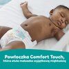 Na zdjęciu widoczne jest niemowlę leżące na plecach, ubrane w pieluchę z kolorowymi wzorami. Na dole zdjęcia znajduje się tekst: "Powłoczka Comfort Touch, która otula maluszka wyjątkową miękkością".