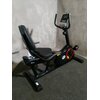 Na zdjęciu znajduje się czarny rower magnetyczny z wygodnym siedzeniem i oparciem, umieszczony na ciemnej wykładzinie. Na obudowie roweru widoczne jest logo "HERTZ".