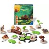 Na zdjęciu znajduje się zestaw elementów do gry logicznej RAVENSBURGER Gravitrax Junior Zestaw uzupełniający Król Lew 23862, w tym różnorodne figurki i elementy toru, a w tle widoczny jest kolorowy karton z grafiką nawiązującą do Króla Lwa. Na opakowaniu 