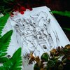 Otwarta książka z ilustracją przedstawiającą zamek wkomponowany w górski krajobraz, otoczona zielonymi i czerwonymi liśćmi. Na stronie widoczny jest fragment tekstu, ale nie jest on w pełni czytelny.