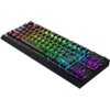 Na zdjęciu znajduje się klawiatura mechaniczna z podświetleniem RGB, z widocznym logo "RAZER" na dolnej części obudowy. Klawisze są podświetlone w różnych kolorach, tworząc efekt tęczy.