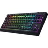 Czarna klawiatura mechaniczna z podświetleniem RGB, na której widoczne są klawisze z oznaczeniami liter, cyfr i funkcji, takich jak "enter", "shift", "ctrl", oraz logo "RAZER" na dolnej krawędzi. Klawiatura ma kompaktowy układ bez bloku numerycznego i pos