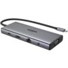 Na zdjęciu widoczny jest hub USB typu C w kolorze szarym z kilkoma portami, w tym HDMI, Ethernet, VGA i audio, oraz plecionym kablem zakończonym wtykiem USB-C. Na powierzchni urządzenia znajduje się napis "UGREEN 4K 60Hz".