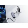 Na zdjęciu znajduje się hub UGREEN CM511 6w1 USB Typu C, pasywny, podłączony do laptopa i zasilacza. Na powierzchni huba widoczny jest napis "UGREEN".