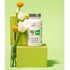Biała butelka suplementu diety "BESTLAB BEST MAG DAY" stoi na zielonym tle obok białych i żółtych kwiatów. Na etykiecie widnieje napis: "Mg", a poniżej informacje o produkcie, w tym "60 kapsułek".