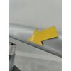 Srebrna powierzchnia z żółtą, błyszczącą strzałką przyklejoną na niej. W tle widoczna jest szara podłoga i fragment metalowego elementu.