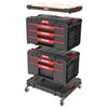 Na zdjęciu widoczny jest zestaw skrzynek narzędziowych QBRICK System One Workshop Drawers Set 4, składający się z czterech czarnych modułów z czerwonymi elementami, umieszczonych na platformie z kółkami. Na każdej skrzynce znajduje się logo "QBRICK" oraz 