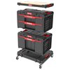 Na zdjęciu widoczny jest zestaw skrzynek narzędziowych QBRICK System One Workshop Drawers Set 6, składający się z kilku czarnych modułów z czerwonymi elementami, umieszczonych na platformie z kółkami. Na każdym module znajduje się logo "QBRICK" oraz drewn