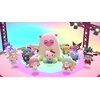 Na kolorowej scenie znajdują się postacie z gry, w tym centralnie umieszczona postać z sercem na brzuchu oraz Hello Kitty w niebieskim stroju. W tle widoczne są reflektory i konstrukcja sceniczna.