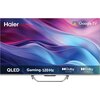 Telewizor z logo Haier i Google TV na ekranie, z kolorowym tłem w odcieniach fioletu i niebieskiego. Na dolnym pasku widnieją napisy: "QLED", "Gaming.120 Hz", "Dolby Vision", "Dolby Atmos".