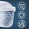 Na zdjęciu widoczny jest filtr wypełniony niebieskimi i czarnymi kulkami, obok którego znajdują się trzy ikony: "50% BIO" z liściem, symbol recyklingu oraz przekreślone plastikowe butelki. Tło jest jednolite, ciemnoniebieskie.