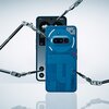 Na zdjęciu widoczny jest niebieski smartfon z przezroczystą obudową, ukazującą wewnętrzne elementy, oraz ekranem z wyświetlonymi ikonami i tekstem "A1". Wokół telefonu znajdują się metalowe ramiona przypominające narzędzia robotyczne.